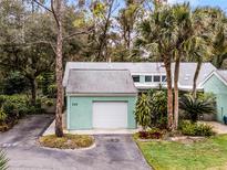 Exterior view of a teal house with a white garage door, palm trees, and landscaping at 717 Glasgow Ct, Winter Springs, FL 32708