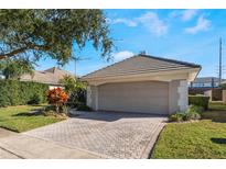 Two-car garage with a brick driveway and manicured landscaping, offering both convenience and curb appeal at 10812 Woodchase Cir, Orlando, FL 32836