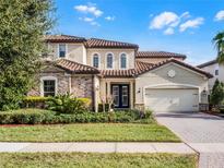 Charming two-story home with a stone facade, red tile roof, paver driveway, and manicured landscaping at 10875 Savona Way, Orlando, FL 32827