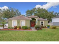 One-story house with green exterior,red door,landscaped yard at 1511 Dunn Cove Dr, Apopka, FL 32703