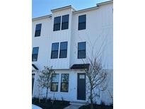 Three-story townhome with white siding, dark gray door, and landscaping at 15112 Grove Lake Dr, Winter Garden, FL 34787