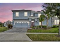 Two-story house with gray siding, gray garage door, and landscaping at 1533 Maidstone Ct, Champions Gate, FL 33896