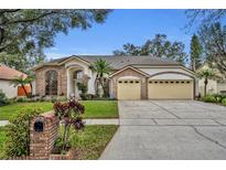 Brick house with three-car garage, manicured lawn, and mature trees at 3838 Gatlin Place Cir, Orlando, FL 32812