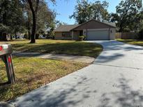 House exterior featuring a two-car garage and a well-maintained lawn at 5581 Aeolus Way, Orlando, FL 32808