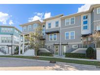 Modern townhome with gray siding, white trim, and a landscaped front yard at 8156 Elion St, Orlando, FL 32827