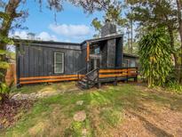 Modern dark-grey house with wood accents, a stone chimney, and a wooden deck at 14421 Parker Rd, Orlando, FL 32832