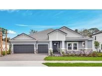 Beautiful single-story home featuring a two-car garage, stone accents, and manicured lawn under a clear blue sky at 2983 Arranmore Dr, Ormond Beach, FL 32174