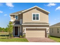 Two-story home featuring a two-car garage, neutral stucco, brick paver driveway and landscaped front yard at 7100 Cherry Pasture Rd, Groveland, FL 34736