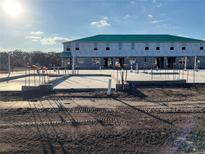 Construction photo of a new two-story townhome featuring a concrete foundation and green roof at 14922 Harvest St, Orlando, FL 32824