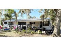 White doublewide mobile home with covered porch, large backyard, and mature trees at 475 80 Foot Rd, Bartow, FL 33830