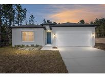 New construction home with white exterior, two-car garage, and landscaping at 8549 Sw 129Th Ln, Ocala, FL 34473