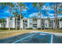 Exterior view of a two-story apartment building with lush landscaping and ample parking at 2230 Cascades Blvd # 207, Kissimmee, FL 34741