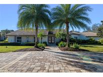 Ranch style home with paver driveway, landscaping, and two palm trees at 5737 Masters Blvd, Orlando, FL 32819