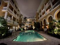 Nighttime view of community pool with patio, chairs and umbrellas surrounded by condo buildings at 860 N Orange Ave # 163, Orlando, FL 32801