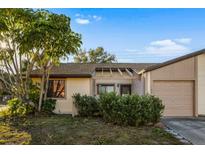 Tan house with brown roof, landscaping, and a garage at 1098 Soria Ave, Orlando, FL 32807