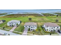 Aerial view of three homes with lake access and lush landscaping at 1551 Gateway Ln, Kissimmee, FL 34746