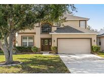 Two-story house with tan siding, brown accents, and a two-car garage at 2760 Curpin Ln, Orlando, FL 32825