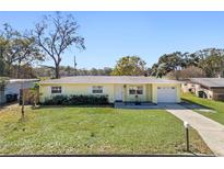 Cute yellow house with a green lawn, driveway, and mature trees at 3710 Sutton Dr, Orlando, FL 32810