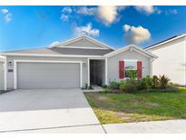 Gray house with red shutters, two-car garage, and landscaped lawn at 445 N Andrea Cir, Haines City, FL 33844