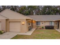 Brick condo with 1-car garage, front patio, and well-manicured lawn at 10738 Se 50Th Ave, Belleview, FL 34420