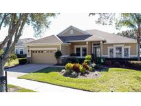 Single-story home with a beige facade, attached garage, and well-manicured landscaping at 250 Bayou Bend Rd, Groveland, FL 34736
