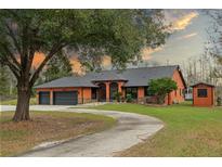 Orange home with three-car garage, curved driveway, and landscaped yard at 3401 Abalone Blvd, Orlando, FL 32833