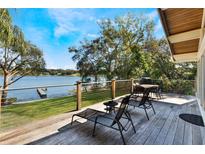 Lakefront deck with lounge chairs and table at 1115 Lake Nettie Dr Dr, Eustis, FL 32726