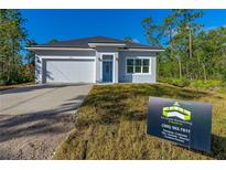 Single-story home with gray exterior, white garage door, and blue front door at 1370 East Pkwy, Deland, FL 32724