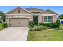 Beige house with two-car garage and landscaped lawn at 2649 Howland Blvd, Deltona, FL 32738