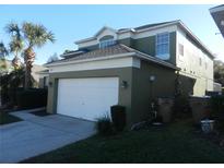 Two-story home with an attached two-car garage, green and white exterior paint, and landscaping at 2803 Lido Key Ct, Kissimmee, FL 34747