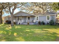 Gray house with white trim, front porch, and large yard at 860 Oak Dr, Groveland, FL 34736