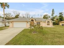 House exterior featuring a one-story home with a front yard and attached garage at 4572 Woodcove Dr, Port Orange, FL 32127