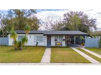White house with gray roof, driveway, and landscaped lawn at 7000 Moderna Way, Orlando, FL 32822