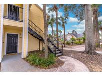 Exterior of a yellow apartment building with black stairs, a sidewalk and tropical landscaping at 1057 S Hiawassee Rd # 1911, Orlando, FL 32835