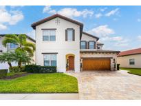 Beautiful two-story home featuring a tile roof, wood garage door, manicured lawn, and lush landscaping at 10824 Royal Cypress Way, Orlando, FL 32836