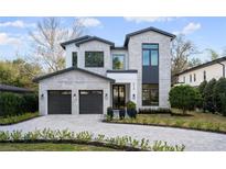 Modern two-story home with gray brick exterior, two-car garage, and a paved driveway at 210 E Lake Sue Ave, Winter Park, FL 32789