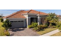 Gray house with a tile roof, driveway, and landscaping at 13370 Alderley Dr, Orlando, FL 32832