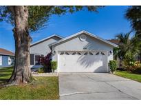 Gray house with white garage door, landscaping, and driveway at 1511 Oak Hill Trl, Kissimmee, FL 34747