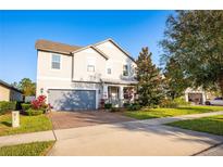 Two-story house with gray siding, paver driveway, and landscaping at 3439 Feathergrass Ct, Harmony, FL 34773