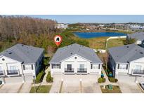 Aerial view of two-story townhouses with attached garages and a pond nearby at 6416 S Goldenrod Rd # 8B, Orlando, FL 32822