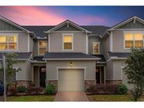Two-story townhome with light beige siding, dark gray roof, and a two-car garage at 1153 Seaside Mist Trl, Kissimmee, FL 34747