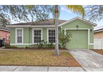 Green house with a two-car garage and well-maintained lawn at 127 Sundown Ct, Davenport, FL 33896