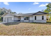 Newly constructed one-story home with gray siding, attached garage, and spacious lawn at 10842 Sw 67Th Ave, Ocala, FL 34476