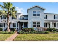 Two-story townhome with light blue exterior, brick walkway, and landscaping at 11868 Pulitzer Pl, Orlando, FL 32832