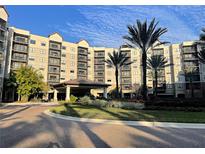 Luxurious condominium building featuring elegant architecture, covered entry, and lush landscaping in a tropical setting at 14501 Grove Resort Ave # 1622, Winter Garden, FL 34787