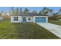 Charming single-story home with a well-manicured lawn and a blue garage door at 15136 Sw 61St Court Rd, Ocala, FL 34473