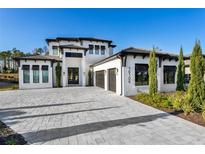 Two-story house with a three-car garage and a paver driveway at 16106 Pendio Dr, Bella Collina, FL 34756