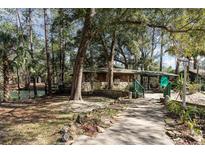 Beautiful home exterior with stone accents, a covered walkway and lush natural surroundings at 221 Se 125Th Terrace Rd, Silver Springs, FL 34488