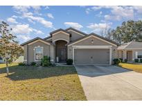 Gray one-story house with two-car garage and landscaped lawn at 3829 Arborvitae Way, Deland, FL 32724