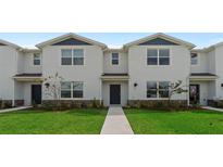Two-story townhouses with modern design, landscaping, and a paved walkway at 5661 Brosnan Rd, St Cloud, FL 34771